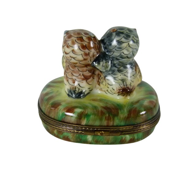 A hand-painted porcelain trinket box from Limoges, France, featuring an adorable pair of wide-eyed owls nestled closely...