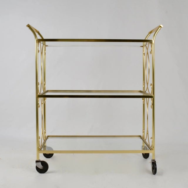 Charming solid brass cocktail cart with three levels and whimsical curved decorations. Black composite wheels. Clear glass...