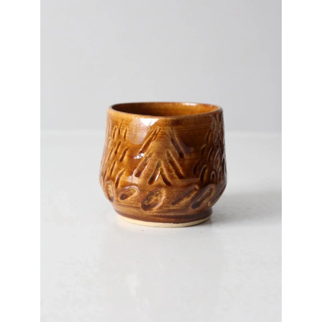 This vintage studio pottery bowl features a warm caramel glaze and a softly rounded form with a small, gently shaped...
