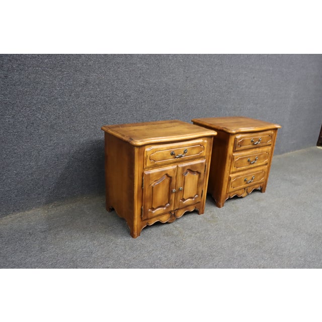 Pair of Ethan Allen nightstands in a warm honey-toned birchwood. The set includes one cabinet-style nightstand with a...