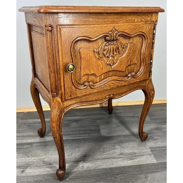 A stunning vintage French Louis-style bedside cabinet , finely handcrafted from solid oak with elegant carved details and...