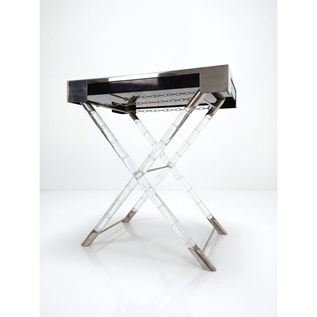 The Maison Jansen-style tray table in acrylic glass and chrome offers a sophisticated example of 1970s French design....