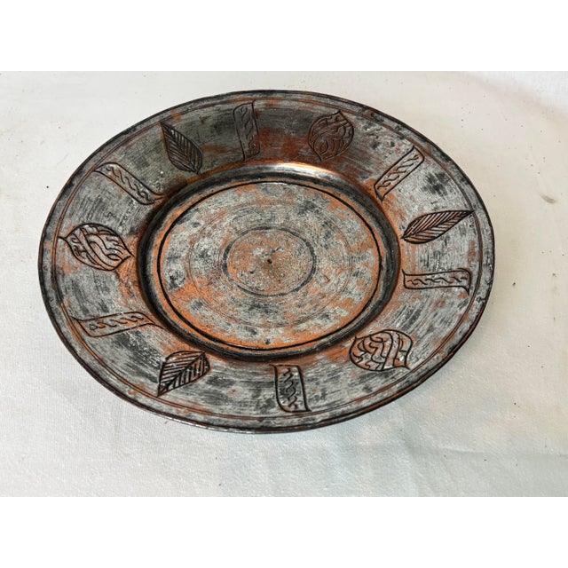 This gorgeous metal platter is gray and copper with incised designs depicting leaves and other shapes. The top surface of...