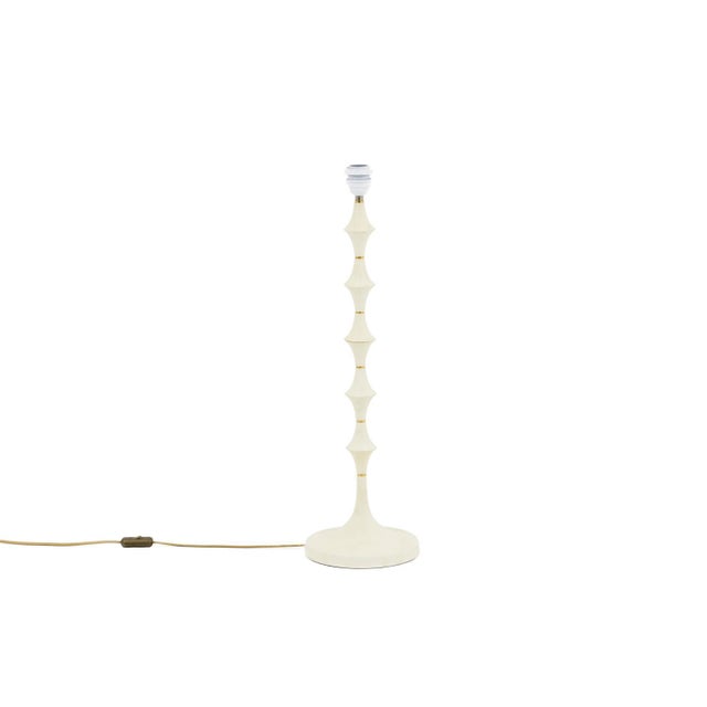 Lamp in white resin and gilt brass. Shaft in stylized stacked hourglasses shape standing on a circular base. Work realized...