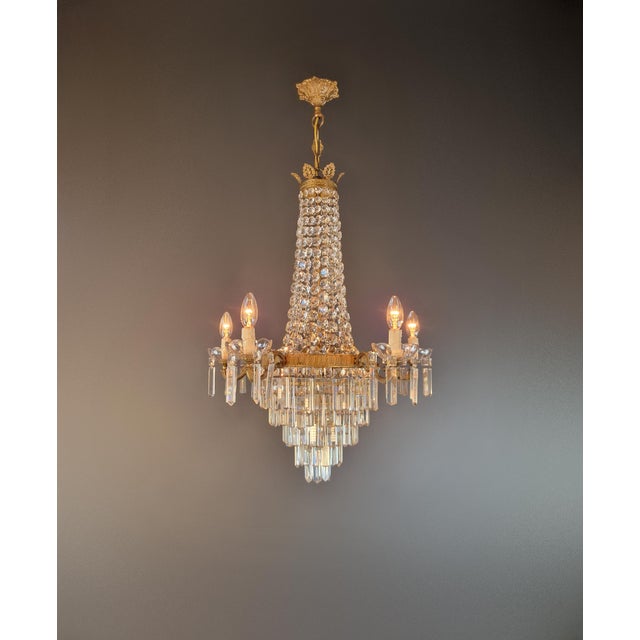 An elegant antique Italian crystal chandelier dating from around 1920. Its tall, slender silhouette blends classical...