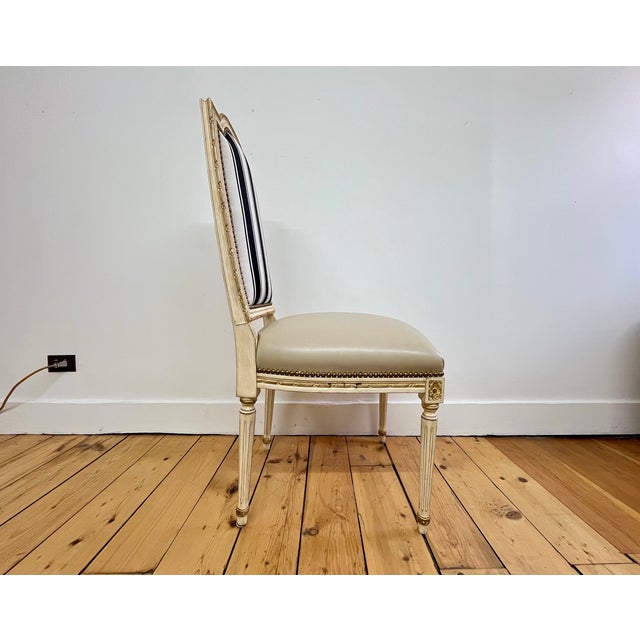 Set of four 1990s reproduction Louis XVI style dining chairs featuring elegantly carved frames with a painted cream finish...
