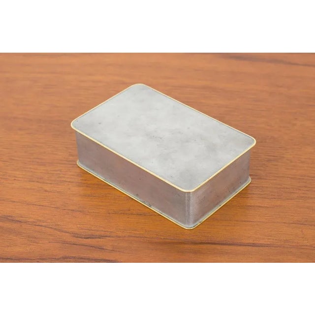 Box designed by Nils Fougstedt. Produced by Firma Svenskt Tenn, this example made in 1953. Made from pewter with brass...