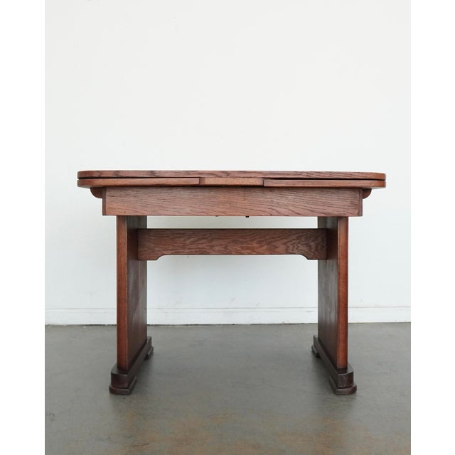 This antique 1920s tiger oak dining table is a beautiful example of early 20th century American craftsmanship. Crafted...