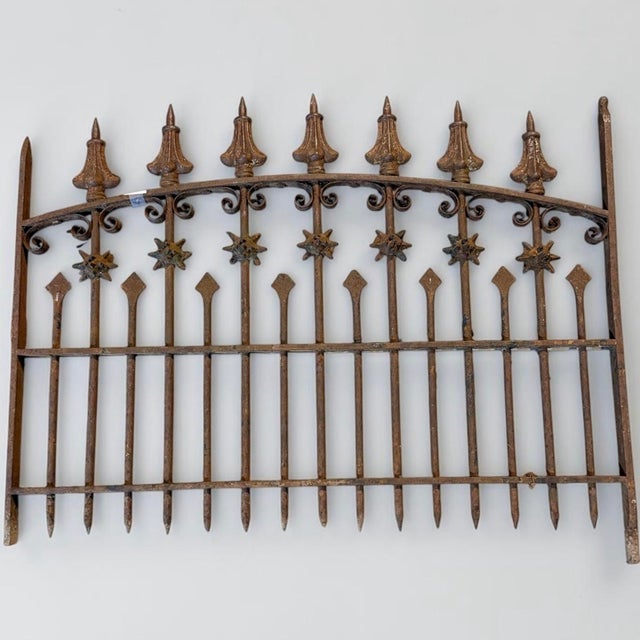 Beautiful matching pair of antique wrought-iron gates with an arched design, ornate scrollwork, starburst accents, pointed...