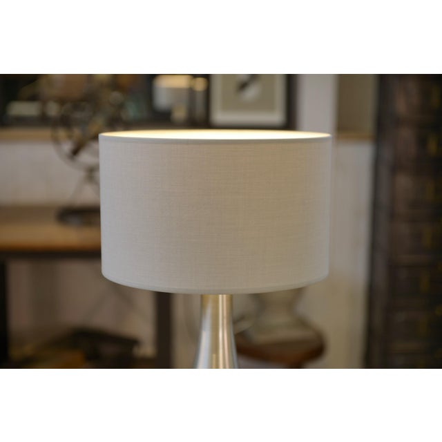 Designer table lamp in brushed aluminum, 1970s. Teardrop-shaped base with flowing lines and a satin finish that...