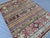 This hand-knotted Super Kazak rug alternates bold rows of diamond medallions in burgundy, green, and ivory with narrow...