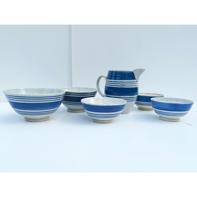 A lovely collection of English pottery, including five bowls and a pitcher, decorated with blue stripes on classic white...