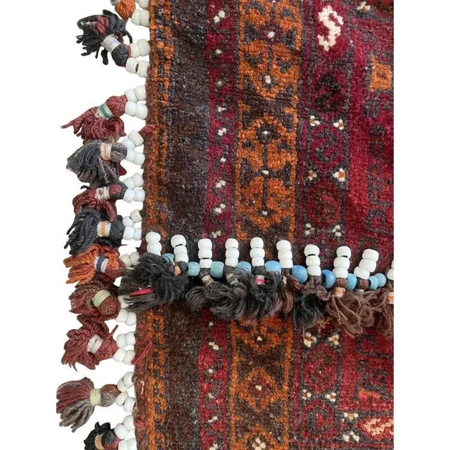Handwoven saddlebag from southwestern Persia. Hand-knotted and tufted front panel with a geometric pattern in deep red,...