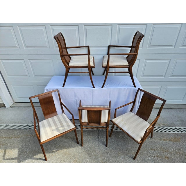 A set of five walnut armchairs with upholstered seats. This set is attributed to T.H. Robsjohn-Gibbings for Widdicomb. The...