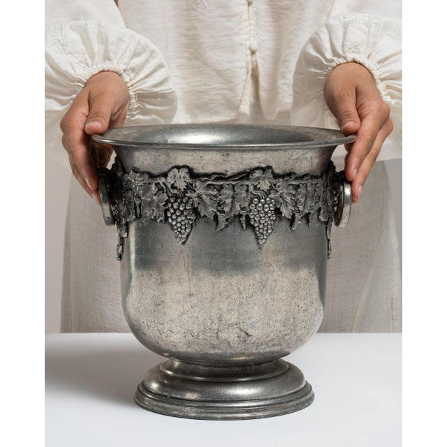 This mid 20th century ice bucket from France is finished in silver. It is fitted with a pair of grape-motif ring handles,...