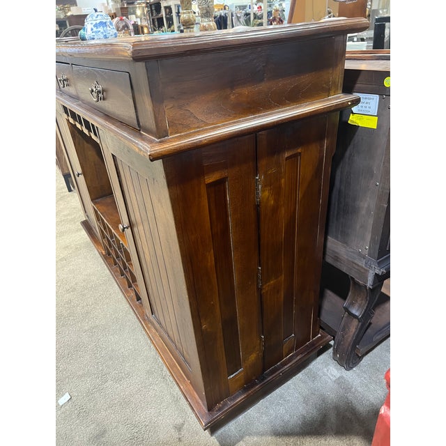 This dark wood three-drawer, two-door dry bar is a timeless blend of traditional craftsmanship and functional entertaining...