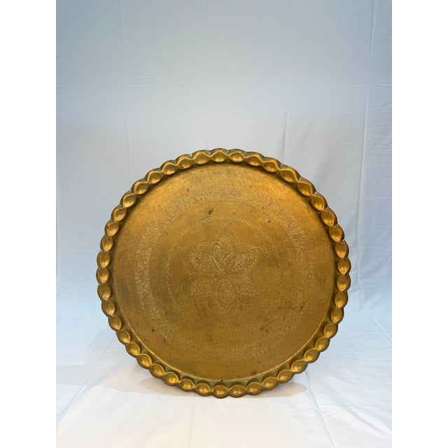 An impressive round brass tray distinguished by intricate engraved botanical ornament and a softly scalloped rim. At more...