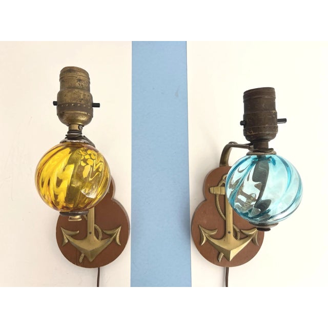 Darling pair of 1950s/60s nautical sconces with solid carved wood back plates accented by gold metal anchors and suspended...
