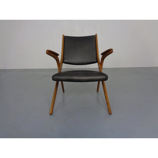 This beech boomerang chair from Louis van Teeffelen for Wébé originates from the 1960s and has black leather upholstery. I...