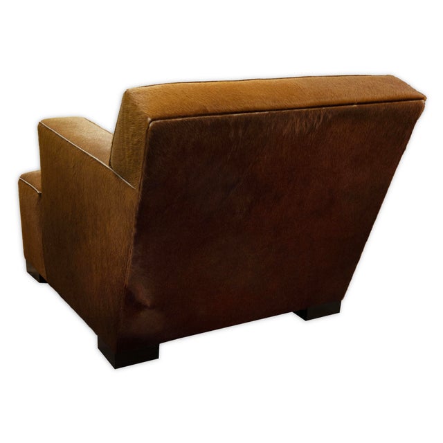 This contemporary club chair features a clean low profile and generous box-form silhouette, wrapped in warm cognac-colored...