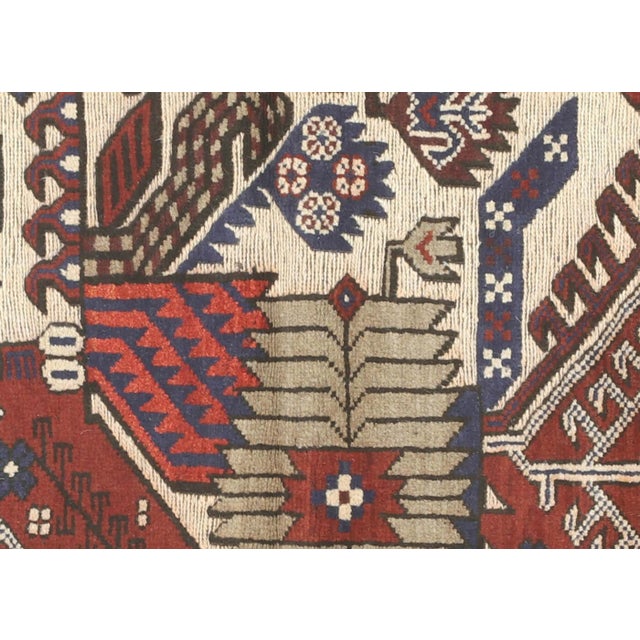 This vintage Afghan Balouch rug, measuring 4'4" x 6'1", is handwoven with wool on a wool foundation by the Baluchi tribes...