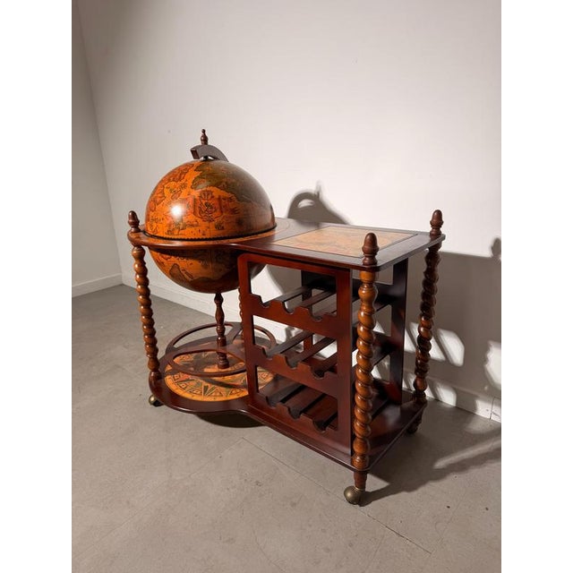 Decorative antique globe bar cart crafted in dark wood and richly decorated with detailed historical world maps. The large...