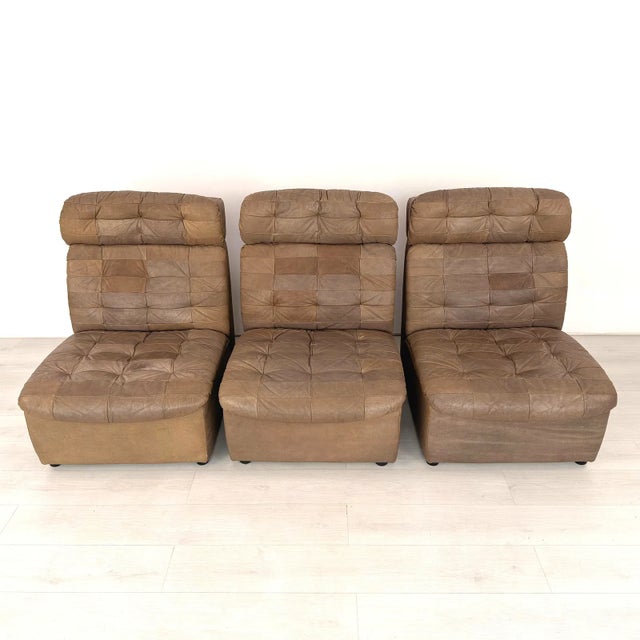 Vintage 1970s three-piece modular sofa featuring richly patinated brown patchwork leather upholstery, deep tufting, and...