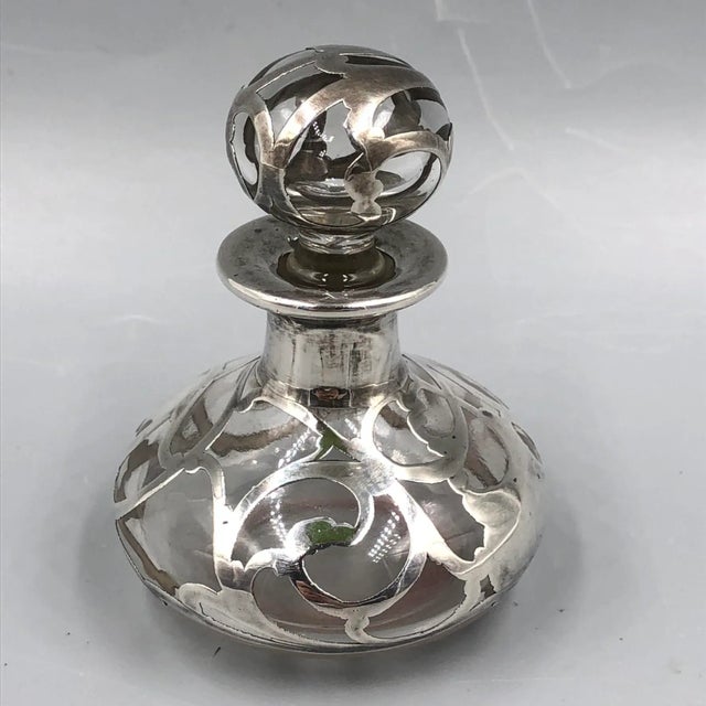 An exquisite and finely crafted antique Art Nouveau bottle with an ornate sterling silver overlay dating from around 1900....
