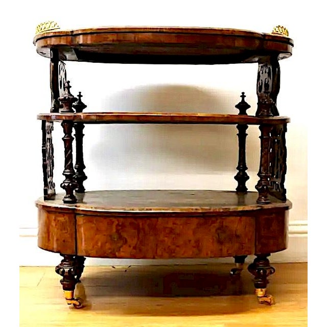 Richly hand carved, this late 19th-century, three-tier bar cart features a painted floral design, brass surround accents,...