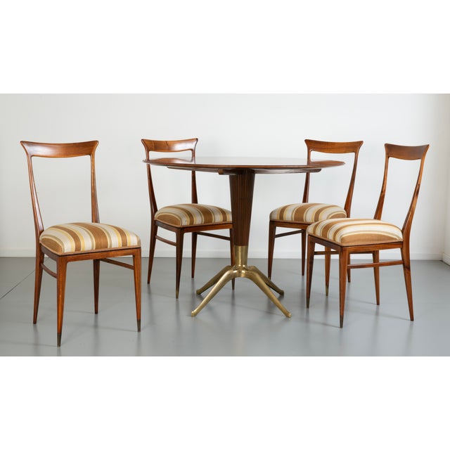 Teak and brass table. Beech chairs with fabric upholstery. This piece is attributed to the mentioned designer/maker. It...