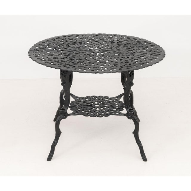 Modern Cast Metal Five-Piece Patio Furniture Set, comprising: a cast iron round table and four armchairs, the table marked...