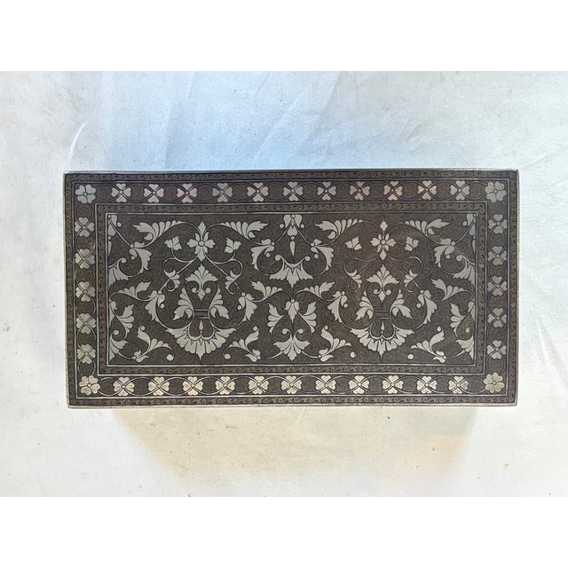 This beautiful brass box depicts silver floral designs.