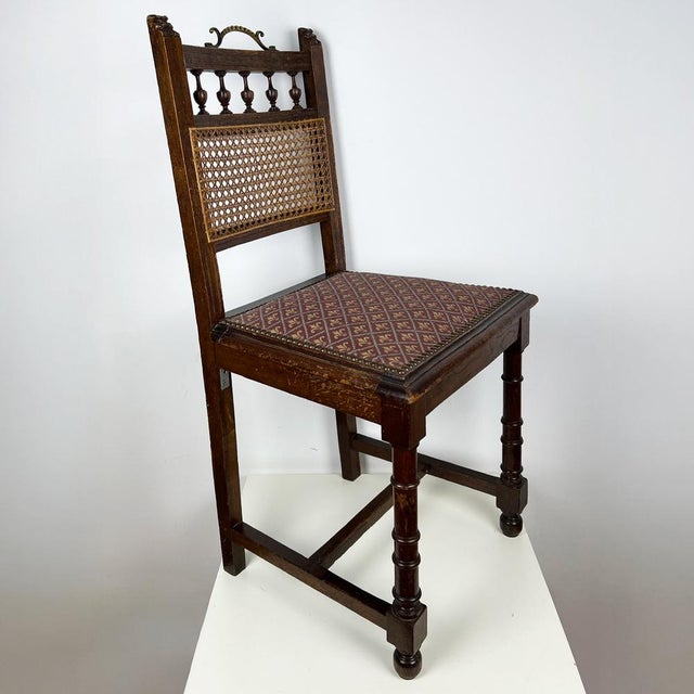 Antique Henry II style oak chair with cane back and carved grotesque details.