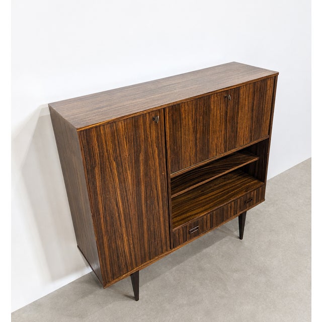 Versatile mid-century vintage highboard combining storage and multiple functions. The main compartment can be used as a...