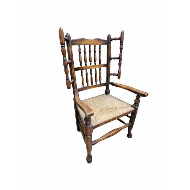 An English spindle back "wing" chair made of Ash with a rush seat, the back with two rows of five spindles with the arms...
