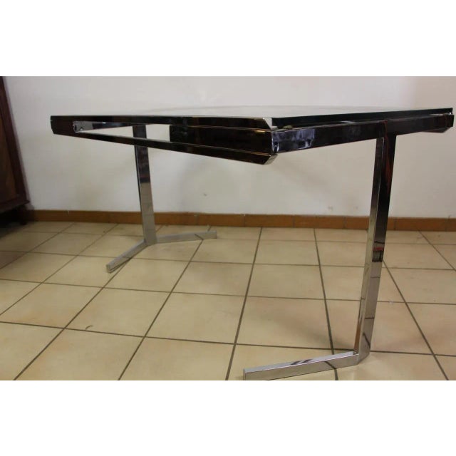 This nickel-plated dining table dates from the 1970s and features a top in glass.