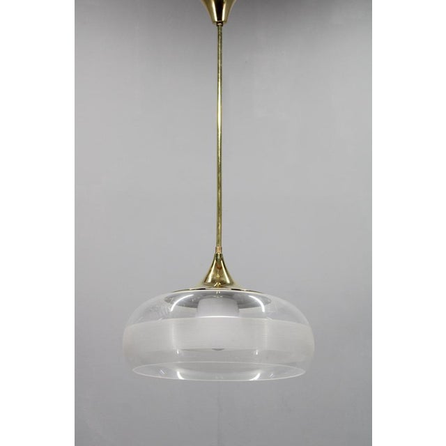 An original italian mid century modern pendant lamp from the 1970s, crafted with a polished brass structure and layered...