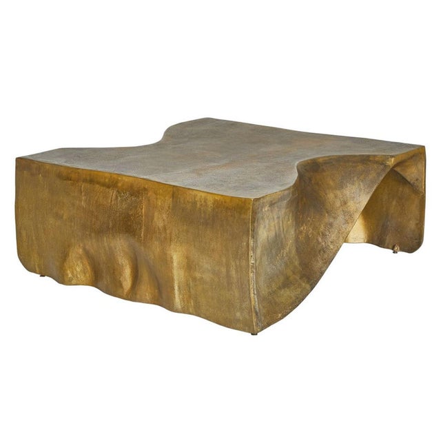 With the fluid silhouette of draped fabric translated into cast aluminum, this sculptural coffee table features softly...