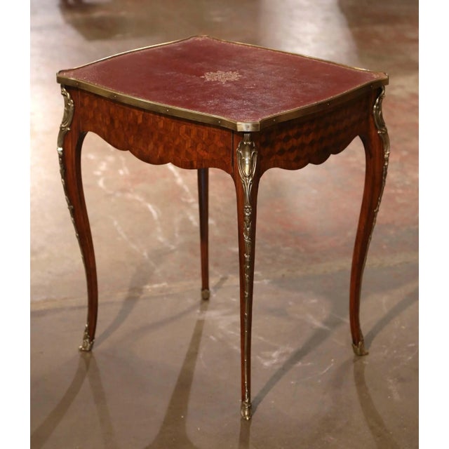 Featuring intricate marquetry and finely detailed gilt bronze mounts, this antique Louis XV style side table reflects the...