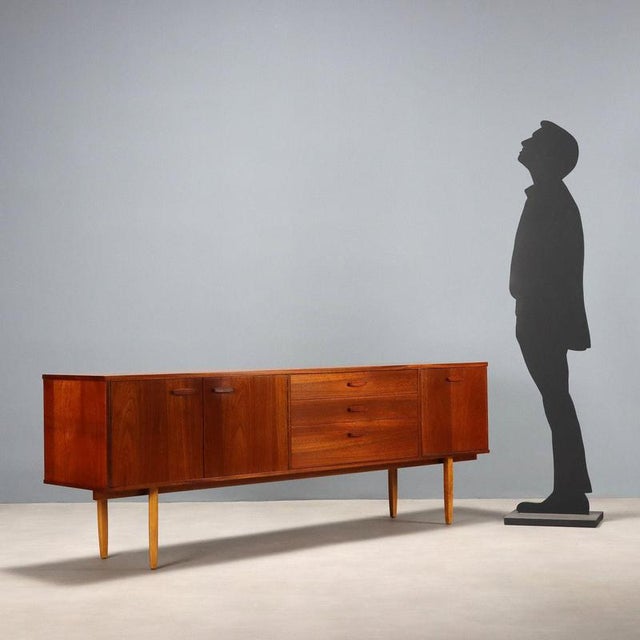 Vintage teak veneered sideboard with a drop-down door, three drawers, and hinged doors. with its clean, elegant lines,...