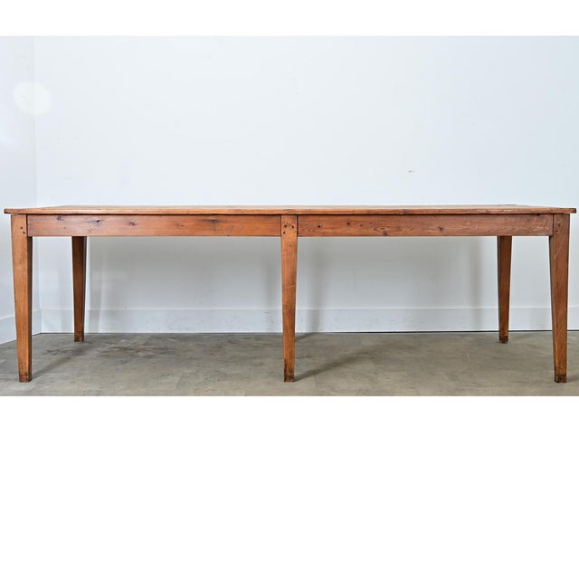 A 19th-century French farm table made from solid pine, circa 1870. The top consists of four long tongue and groove planks...