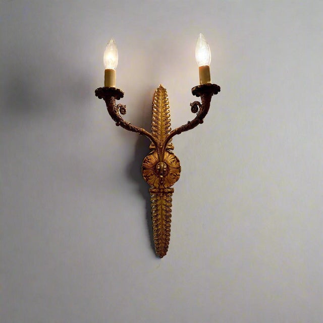 A cast bronze two-light wall sconce with an applique and leaf motif, designed by De Coene Frères from Belgium, circa 1930.