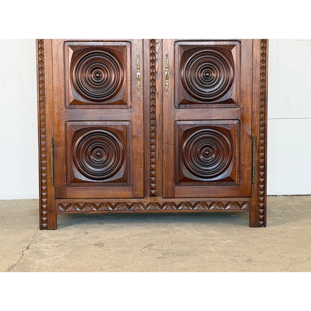 A carved oak two-door armoire, attributed to Charles Dudouyt, France, 1940s. The facade is dominated by six deeply carved...