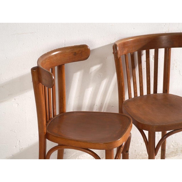 A set of two antique armchairs in bentwood, with a horseshoe back wrapping into the arms, over vertical splats and a...