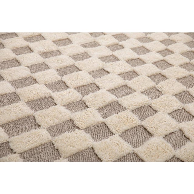 A timeless grid, softened by the hand. A classic checkerboard pattern unfolds across this piece, alternating squares of...