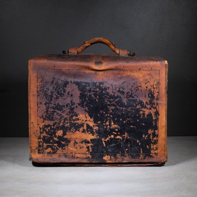 ABOUT An early 20th-century camera case dating from approximately the 1900s to the 1930s, this rugged attaché-style case...