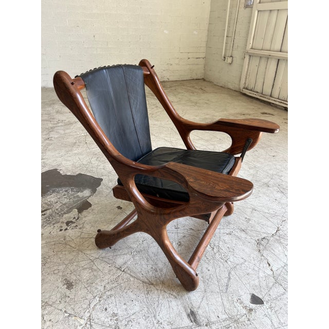 Gorgeous sculpted rosewood rocking lounge chair with perfectly patina'd black leather designed by Don Shoemaker. In...