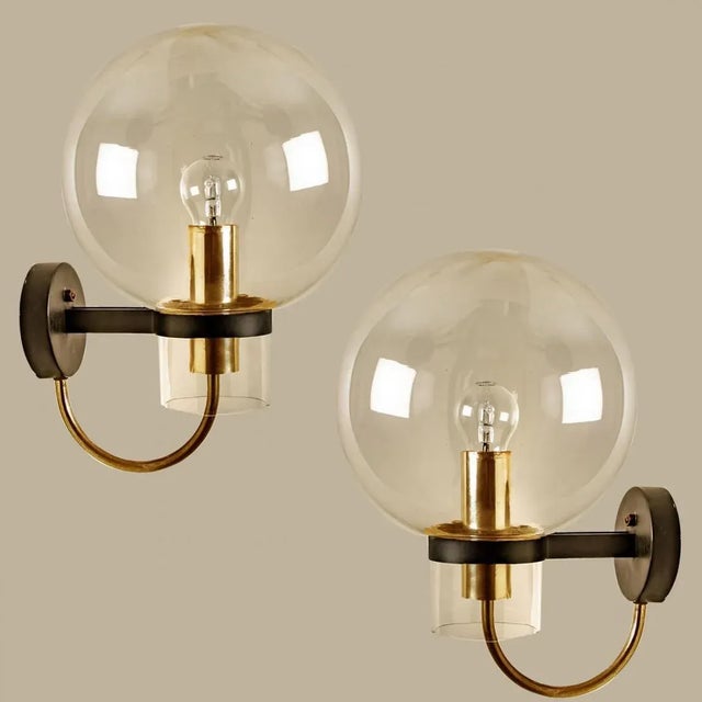 Large quantity of beautiful hand blown clear glass wall lights with brass details. Designed and manufactured by glashütte...