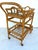 A two-tier bamboo bar cart with a removable tray. The front feet are made of wood, and the back feet are brass casters.