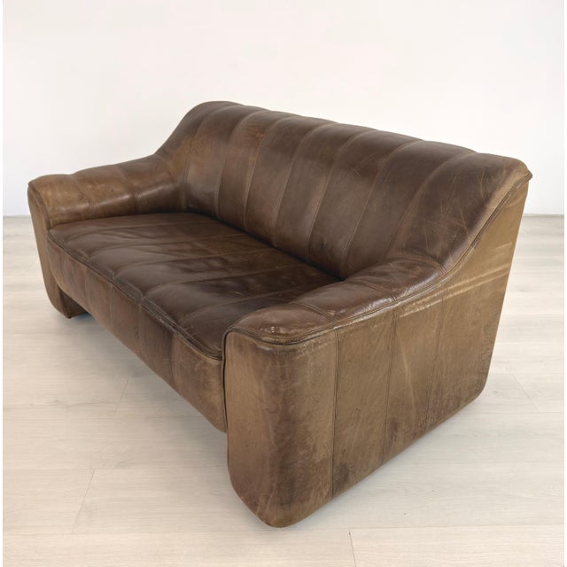 Dimensions: H 29” x W 54.5” x D 34.5” x SH 16.5” Vintage Buffalo brown leather two-seater sofa from De Sede, model DS 44....